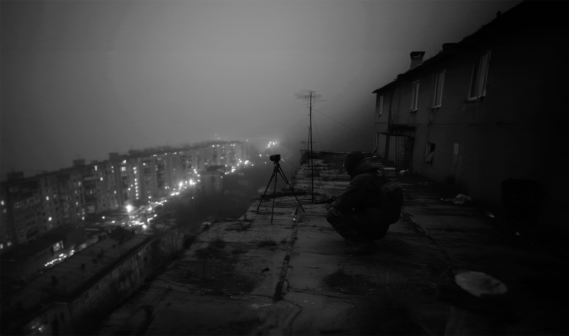 Operator on rooftop overlooking a city at night